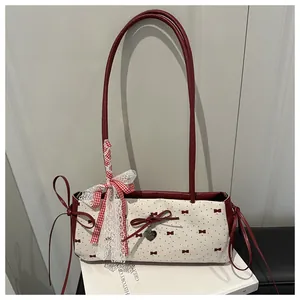 Detail of canvas tote bag with red bows, lace trim, and polished heart pendant decoration