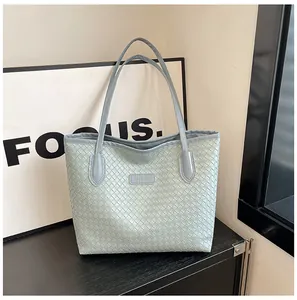 Detail of mint green woven tote bag with premium leather handles and fashion logo