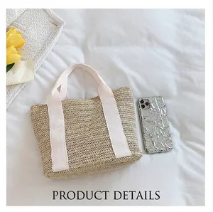 Top view of beige straw tote bag with canvas handles and a phone for size reference