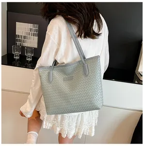 Detail of grey woven tote bag featuring intricate Intrecciato texture and shoulder strap
