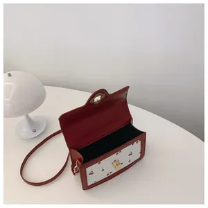 Detail view of the open cherry print crossbody bag with golden twist lock and red leather frame