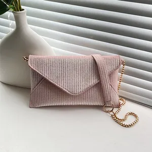 Elegant pink rhinestone envelope clutch with gold chain strap on minimalist background
