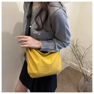 Detail of bright yellow canvas crossbody bag with adjustable black strap on a model