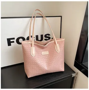 Detail of pink woven tote bag with Fashion & Bags leather tag on a smooth surface