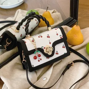 Cute cherry print crossbody bag with woven handle and floral lock on cream fabric