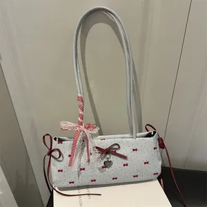 Light blue shoulder bag with red bow prints and heart pendant in a box