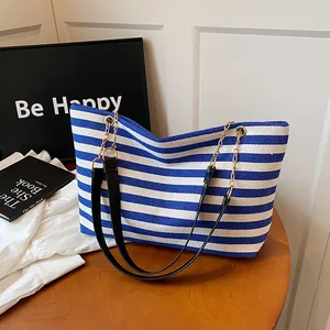 Blue and white striped canvas tote bag with leather chain straps on a wooden table