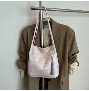 Detailed view of pink jacquard shoulder bag with silver pavilion pattern and long grey tassel