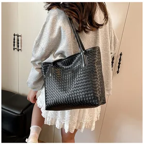 Close-up of a black woven tote bag showing the intricate texture and dual shoulder straps