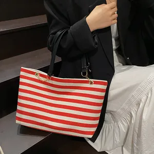 Red and white striped canvas tote bag with black leather handles and gold metal chain