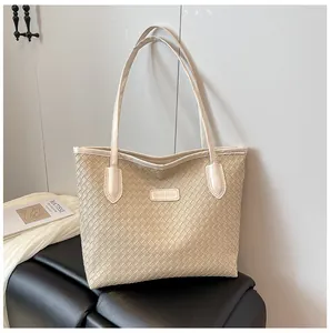 Close-up of woven tote bag texture with fashion label and slim shoulder straps
