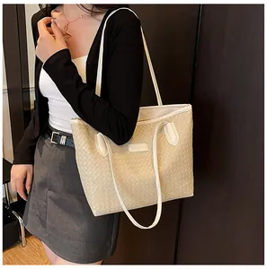 Close-up of beige woven tote bag with fine cross-weave texture and slim shoulder straps