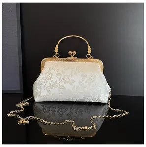 Detail of vintage white floral jacquard evening bag with gold metal handle and chain