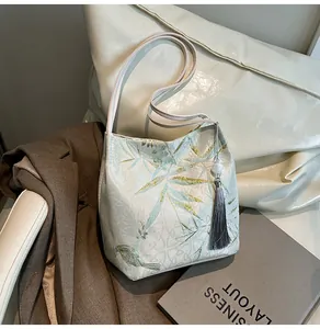 Detail of bamboo pattern jacquard shoulder bag with tassel and gold embroidery accents