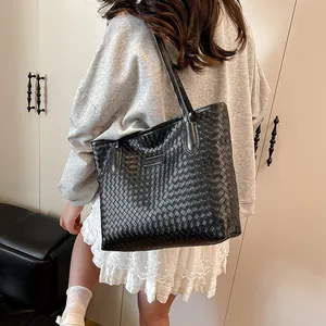 Chic black woven large capacity tote bag worn by a model for a trendy commute look