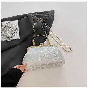 Macro view of floral embroidery on a white evening bag with golden metal frame handle