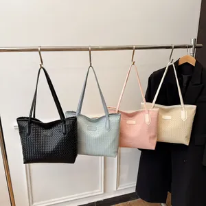 Large woven leather tote bags in four colors hanging on a display rack for daily commute