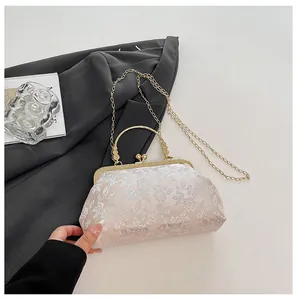 Detailed close-up of pink floral embroidery and vintage gold metal handle of the handbag