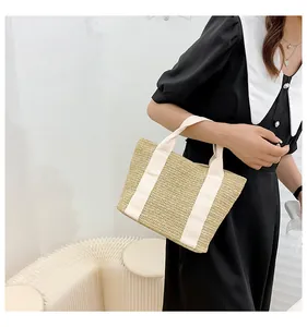 Detail of V-shape woven straw handbag with creamy white canvas handles for summer beach