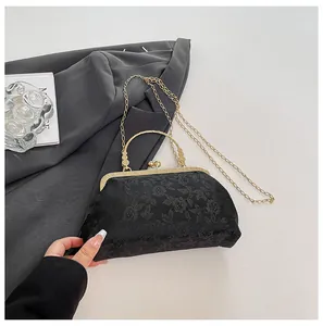 Detail of vintage black floral jacquard handbag with elegant gold metal frame and handle