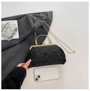Detail of vintage black lace clutch with hollow metal handle and golden chain strap