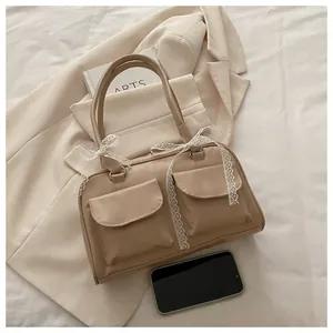 Détail du sac à main beige en simili cuir avec nœuds en dentelle blanche et deux poches