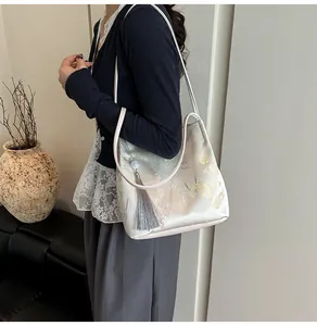 Detail of elegant Chinese style floral embroidery and silk tassel on the ivory shoulder bag