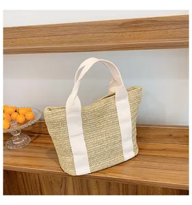 Détail d'un sac à main en paille avec des sangles en coton blanc sur bois naturel