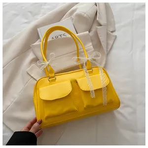 Détail d'un sac bandoulière jaune vif avec nœud en dentelle et deux poches à rabat devant