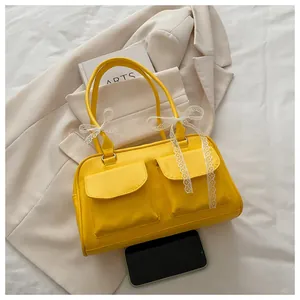 Détail du sac à bandoulière jaune avec nœuds en dentelle blanche et doubles poches avant