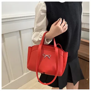 Detailed close-up of a vibrant red leather handbag with a silver metal bow buckle accessory