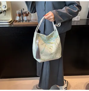 Detail of bamboo leaf jacquard fabric on a green bucket bag with a gray tassel charm