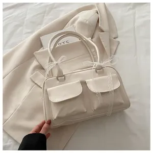 Détail du sac à main en cuir crème avec deux poches et nœud en dentelle blanche élégant