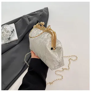 Detail view of white floral jacquard fabric and golden metal clasp with sphere lock