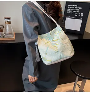 Detail of light green jacquard shoulder bag with bamboo leaf pattern and grey tassel charm