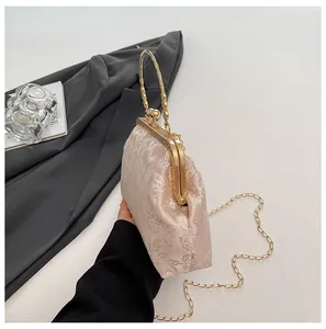 Détail d'un sac à main brodé rose clair avec fermoir et poignée en métal doré