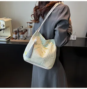 Detail of light green jacquard tote bag with bamboo patterns and grey silk tassel charm