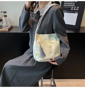 Detailed view of pale green jacquard shoulder bag with bamboo leaf pattern and grey tassel