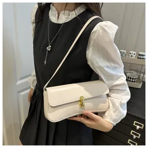 Side view of cream leather shoulder bag with gold twist lock on a fashion model