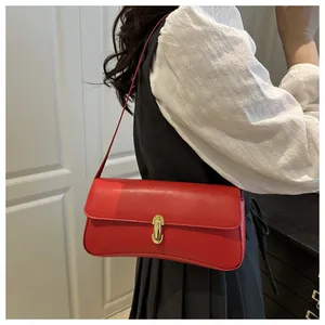 Detail of a bright red baguette shoulder bag featuring a stylish gold metal lock buckle