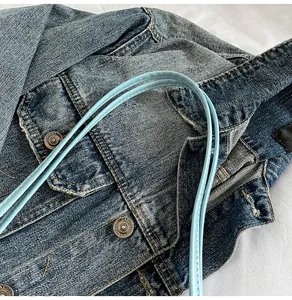 Detail of light blue shoulder bag straps with fine stitching on denim background