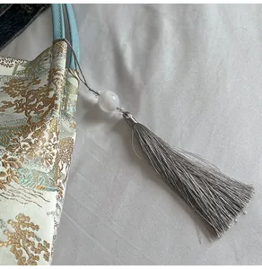 Detail of bamboo jacquard embroidery on handbag with pearl and grey tassel pendant