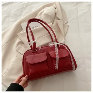 Détail du sac à bandoulière rouge foncé avec nœud en dentelle blanche et deux poches