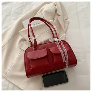Détail du sac oreiller rouge avec rubans en dentelle blanche et doubles poches chic