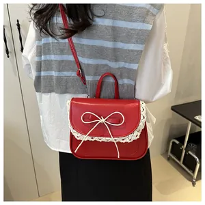 Dettaglio borsa quadrata in pelle rossa con bordi in pizzo bianco e fiocco decorativo