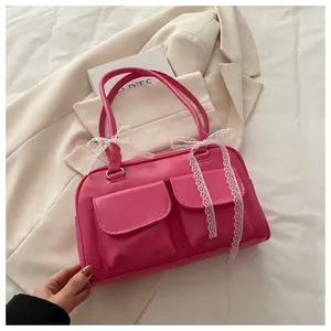 Détail du sac oreiller rose avec nœuds en dentelle blanche et deux poches avant