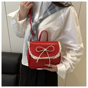 Dettaglio della borsa rossa con bordo in pizzo bianco e fiocco su uno sfondo bianco