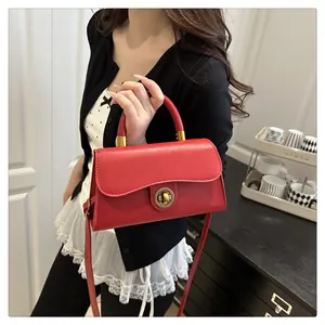 Macro detail of red leather bag featuring a vintage round metal lock and curved flap edge