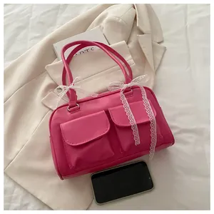 Détail du sac polochon rose vif avec nœud en dentelle et doubles poches à rabat avant