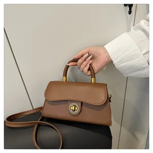 Close-up of retro leather handbag featuring a vintage gold circular twist lock and handle